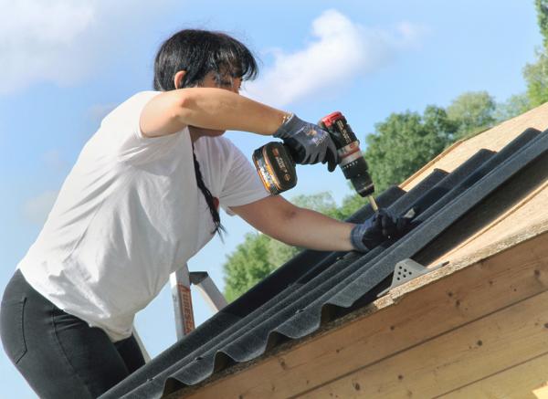 Ein Mann verlegt ONDULINE EASYFIX auf einem Gartenhausdach.