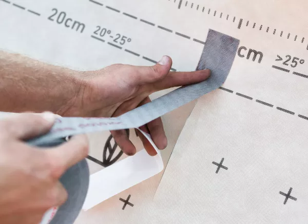 Ein Mann klebt etwas mit ONDUTISS UNO MIX UV3B TAPE zusammen.