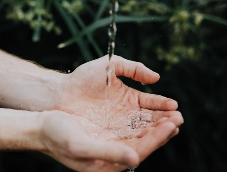 Hände in einem Wasserstrahl.