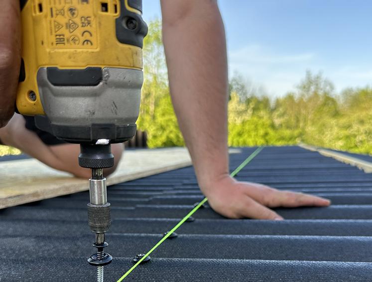 Ein Mann schraubt Wellplatten beim Overroofing auf sein Gartenhaus.