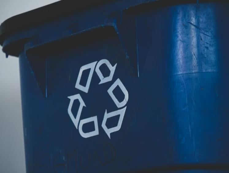 Eine blaue Mülltonne mit Recyclinglogo.